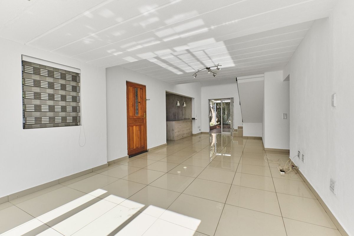 Spacious open-plan living area featuring polished tile flooring, a built-in bar, and direct access to the rear patio through sliding glass doors.