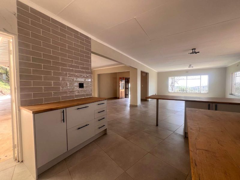 Spacious open-plan living and kitchen area featuring modern subway tile backsplash, wooden countertops, and neutral tiled flooring throughout.