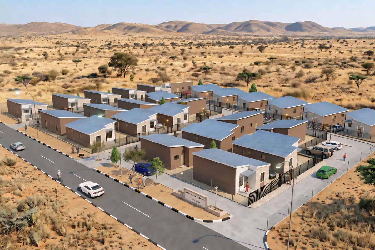 An aerial perspective of a modern townhouse development complex featuring multiple residential units, paved access roads, and perimeter fencing in a desert landscape.