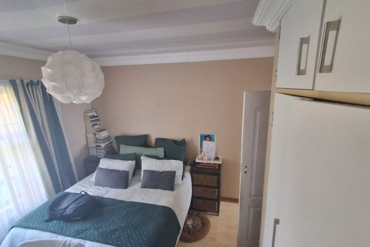 A cozy bedroom featuring built-in cabinetry, crown molding, and natural light from the window.