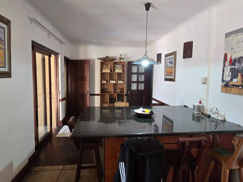 A functional kitchen area featuring a large granite-topped island, pendant lighting, and direct access to the outdoor area via sliding glass doors.
