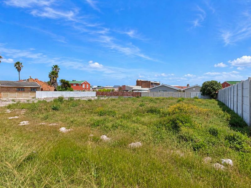 A vacant residential plot featuring established boundary walls, ready for development in a suburban setting.