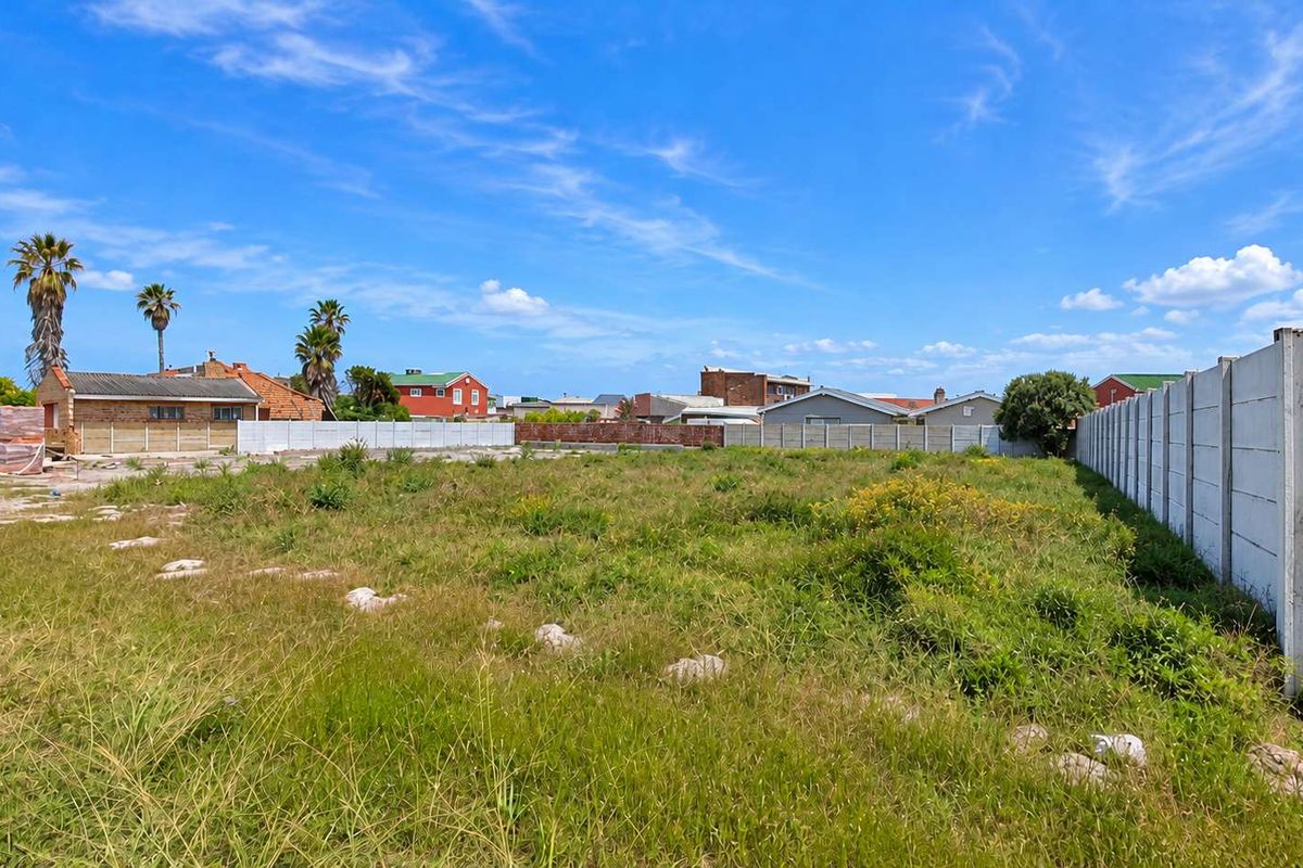 A vacant residential plot featuring established boundary walls, ready for development in a suburban setting.