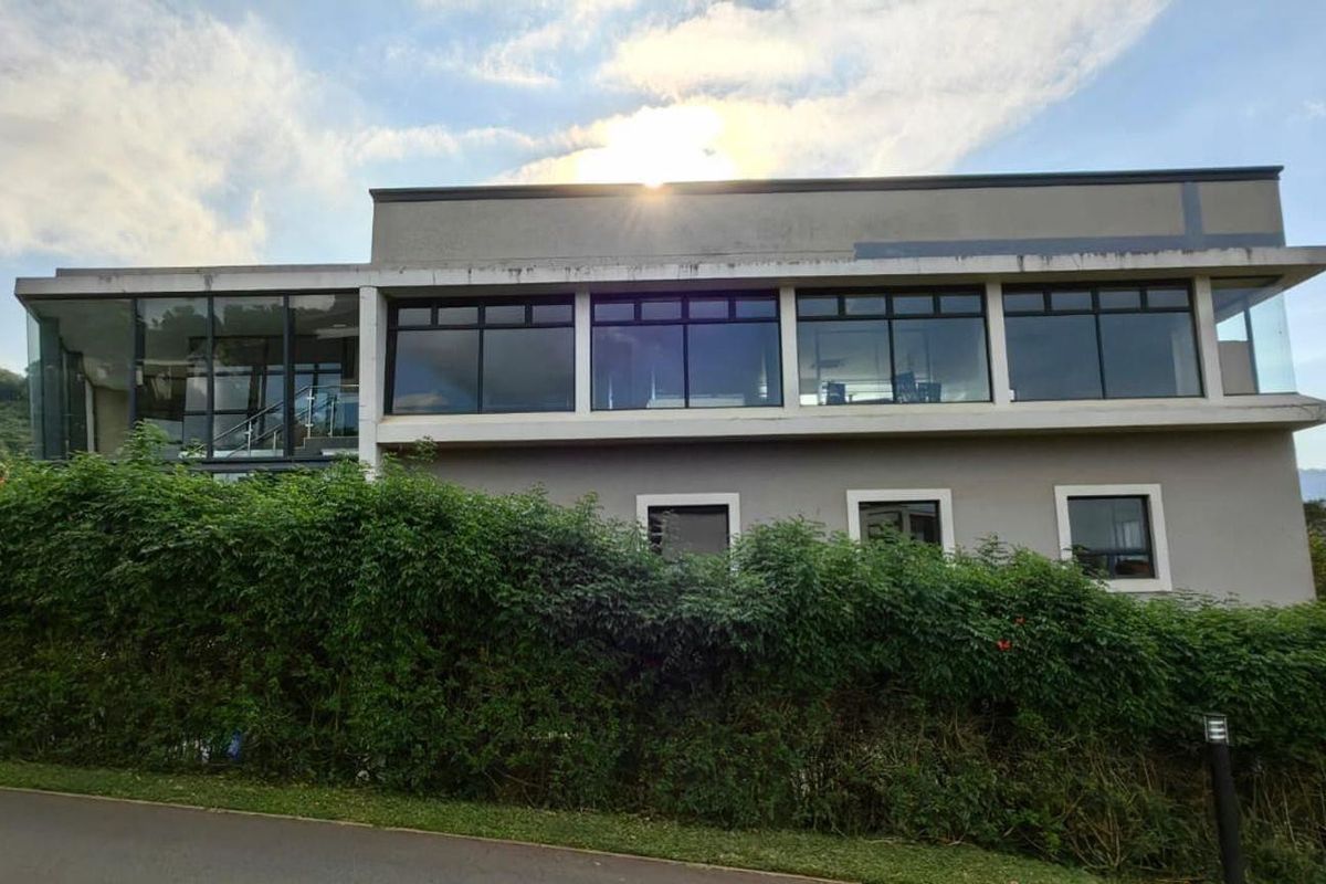 Exterior view of a multi-level commercial building featuring large glass windows, concrete framing, and surrounding landscaped greenery.