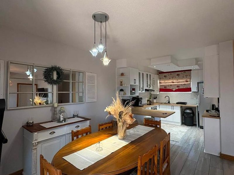 Open-plan dining and kitchen area featuring tiled flooring, modern cabinetry, and a breakfast bar, creating a functional and connected living space.