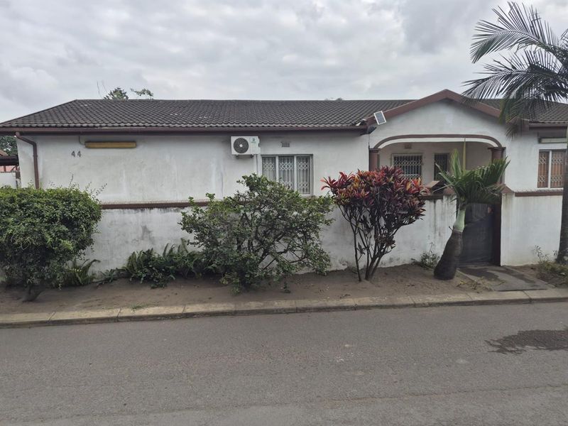 Front elevation of a single-story house featuring a tiled roof, security bars on windows, and an external air conditioning unit.
