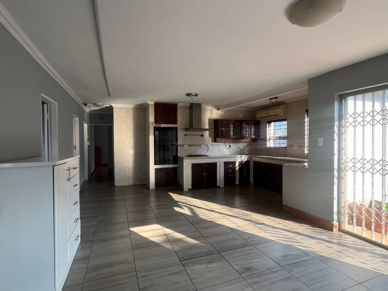 Spacious open-plan kitchen and living area featuring tiled flooring, built-in cabinetry, and direct access to an outdoor patio through a secure sliding door.