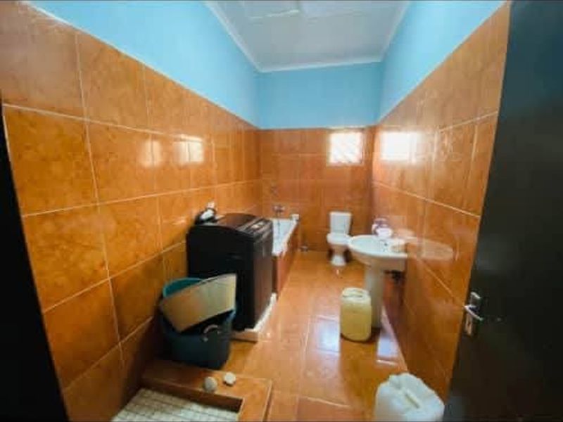 A functional bathroom featuring tiled walls and flooring, equipped with a pedestal basin, toilet, and bathtub.