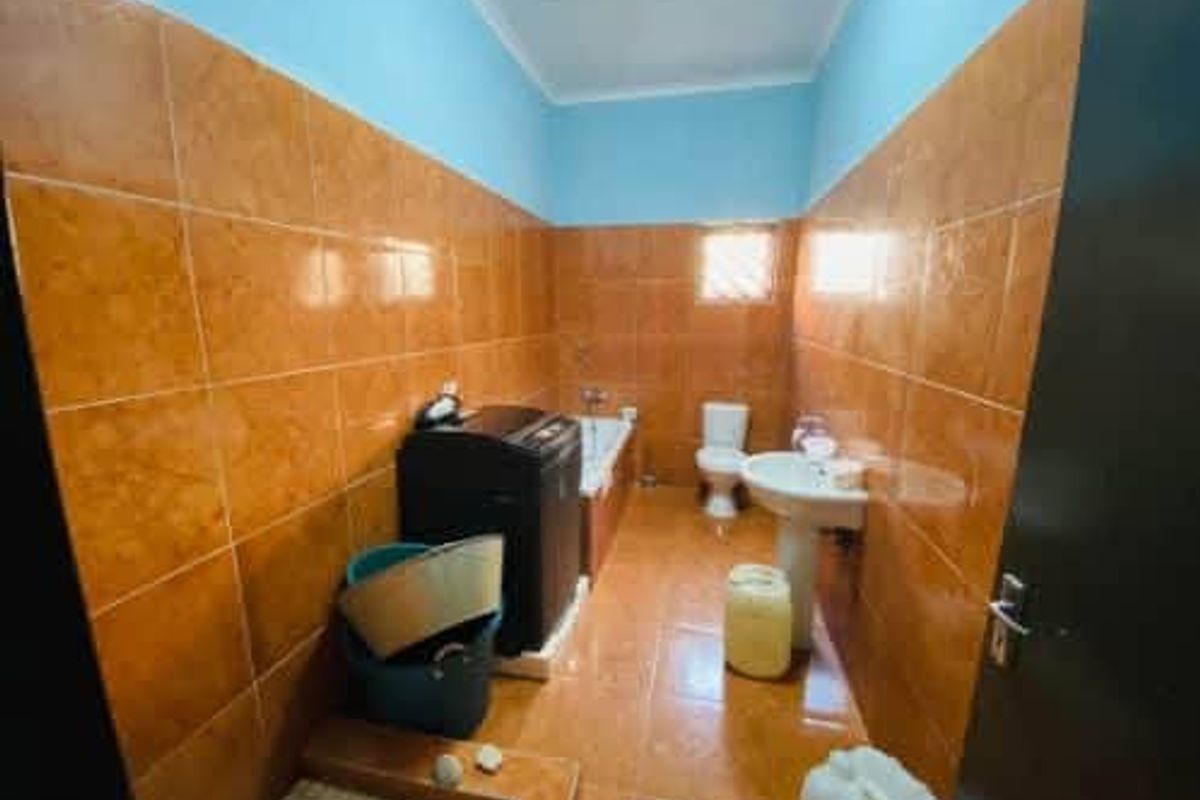 A functional bathroom featuring tiled walls and flooring, equipped with a pedestal basin, toilet, and bathtub.