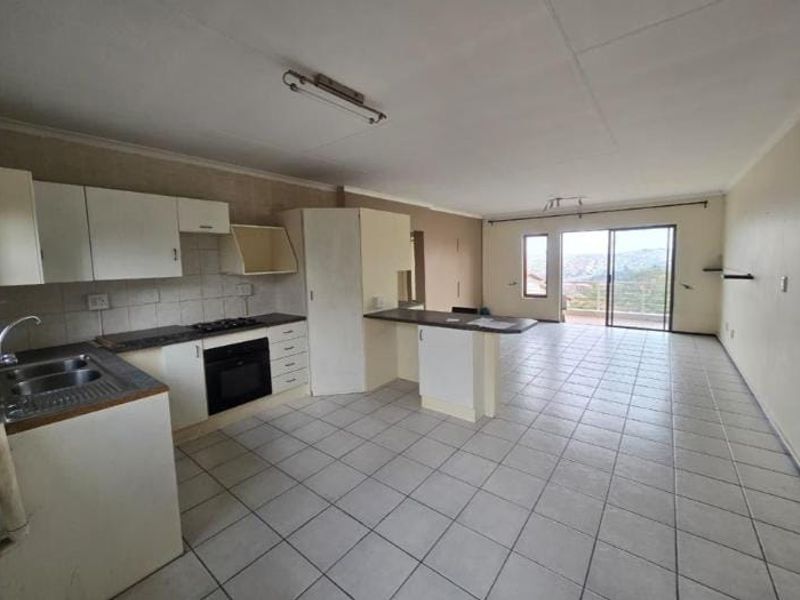 Spacious open-plan kitchen and living area featuring tiled floors, built-in cabinetry, and sliding doors leading to an outdoor space with scenic views.
