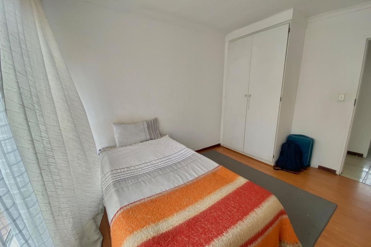 A bedroom featuring laminate flooring and a built-in wardrobe with white doors.