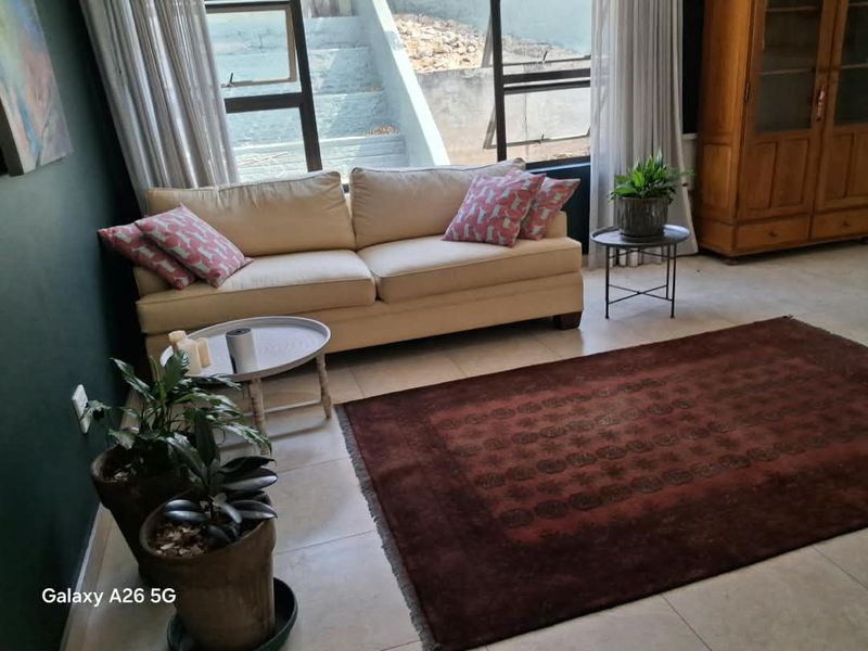 A living room area featuring large windows that provide natural light and tiled flooring throughout.