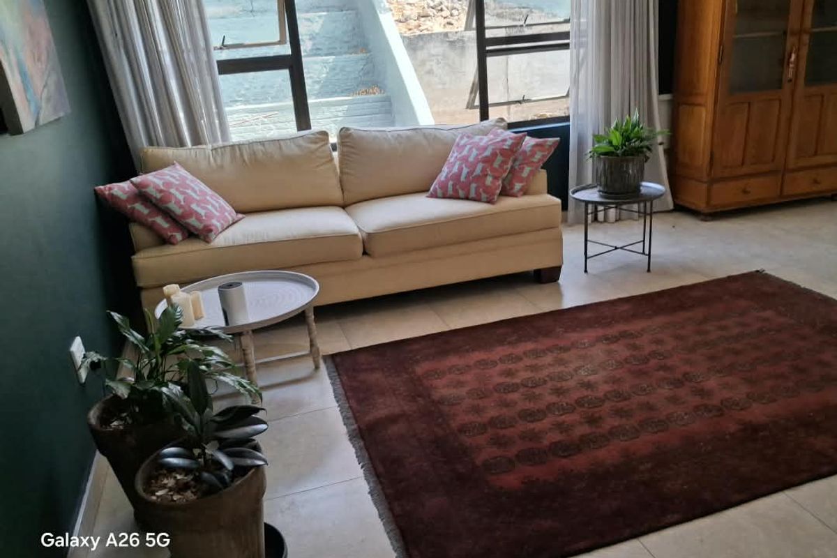 A living room area featuring large windows that provide natural light and tiled flooring throughout.
