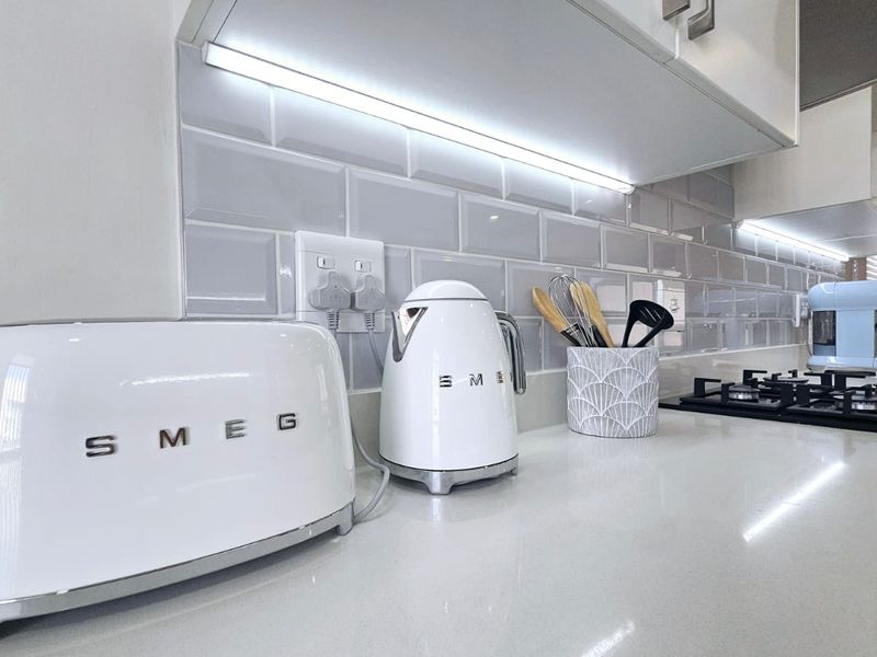 Modern kitchen featuring a clean quartz countertop, subway tile backsplash, integrated under-cabinet lighting, and a built-in gas hob.
