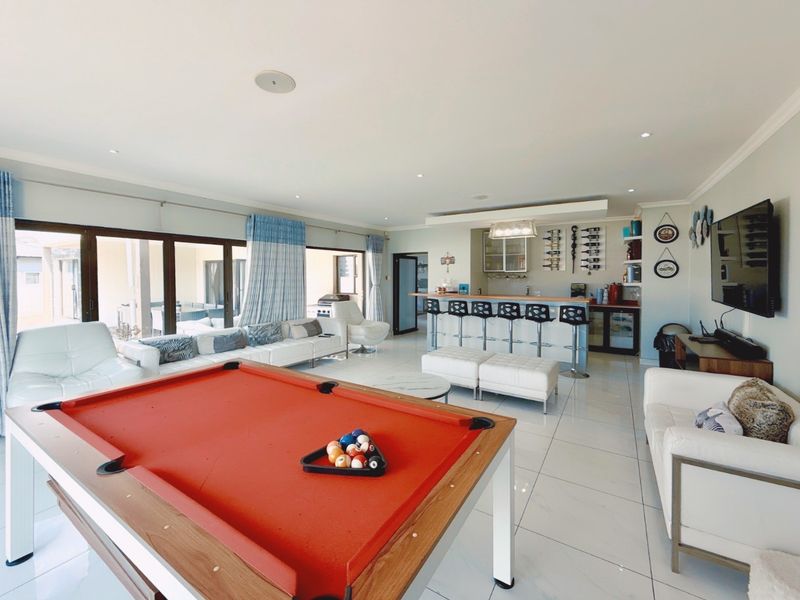 Spacious open-plan living and entertainment area featuring a built-in bar, tiled flooring, and large sliding doors opening to the patio.
