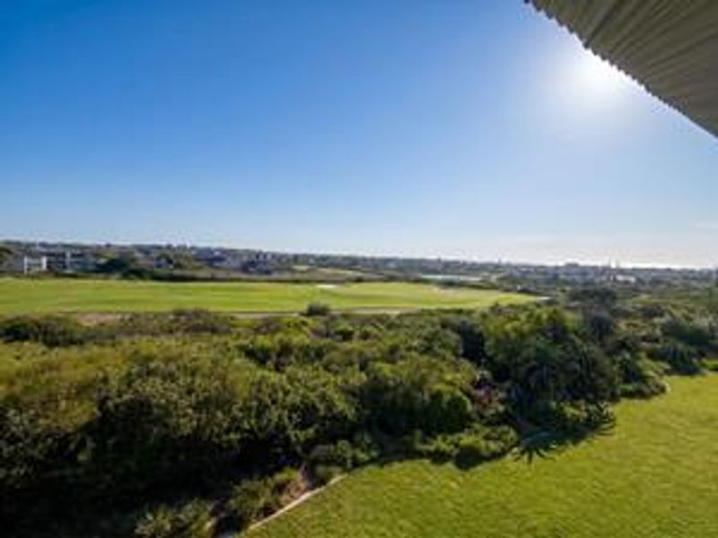 Elevated view overlooking a green golf course and surrounding landscape, captured from an upper level balcony.