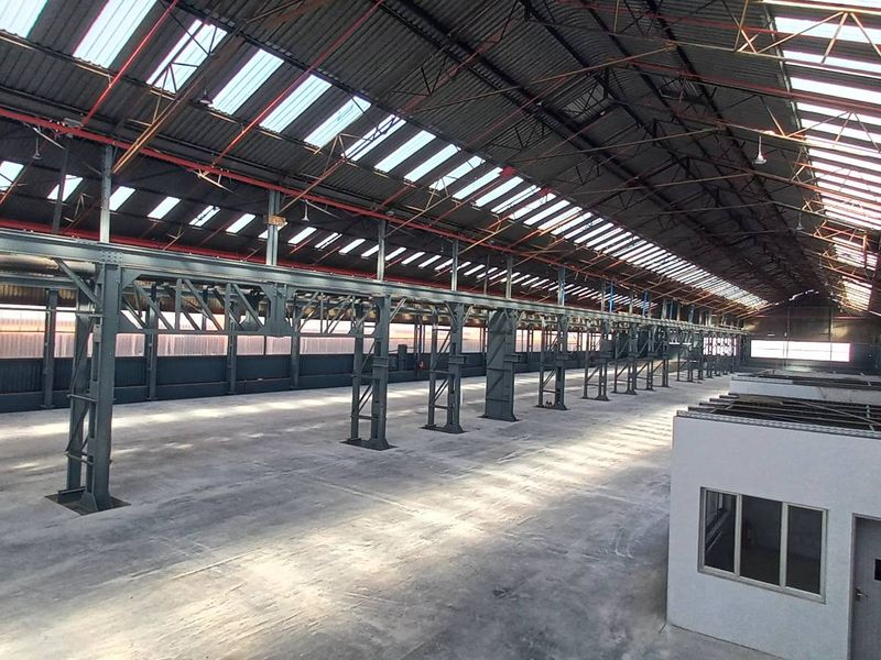 Expansive industrial warehouse space featuring high ceilings, steel portal frame construction, integrated skylights, concrete flooring, and a dedicated internal office structure.