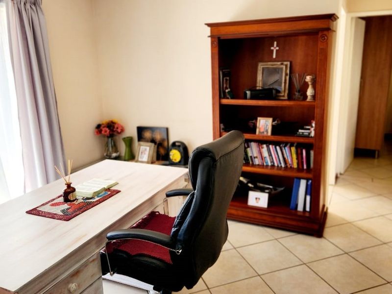 A functional home office space featuring neutral wall tones and tiled flooring, providing a quiet area for work or study.