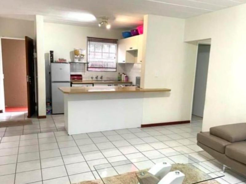 Open-plan living area featuring a functional kitchen with a breakfast bar and tiled flooring throughout.