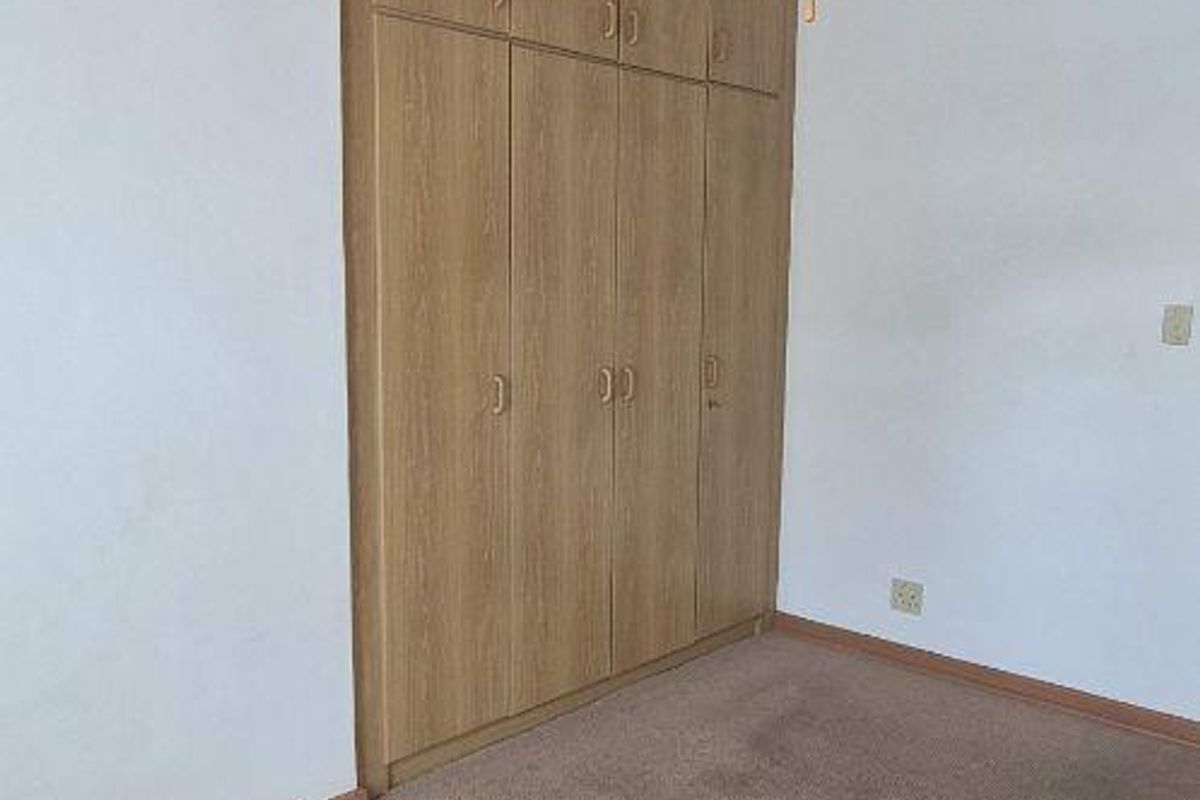 A bedroom featuring built-in wooden cabinetry, a timber-clad ceiling with a fitted ceiling fan, and carpeted flooring.