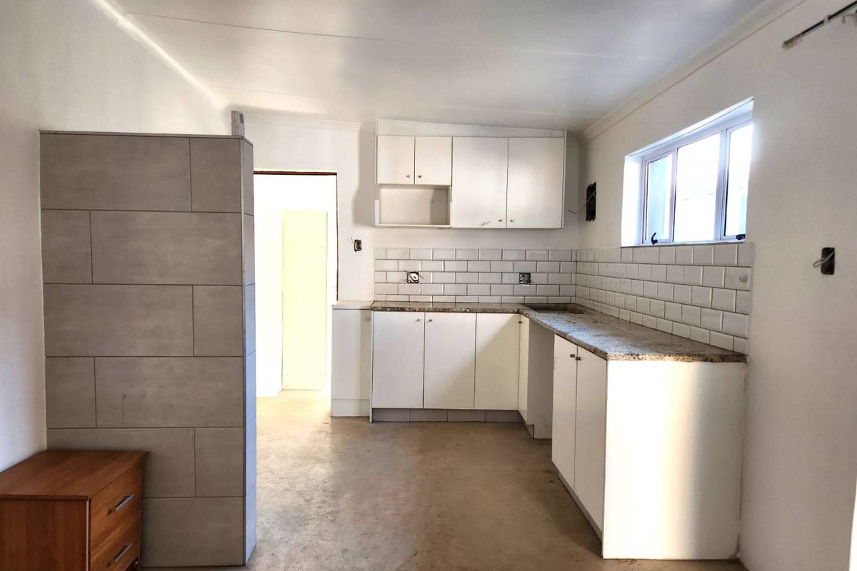 A functional kitchen space featuring white cabinetry, granite countertops, and subway tile backsplash, currently awaiting final finishing touches and electrical installations.