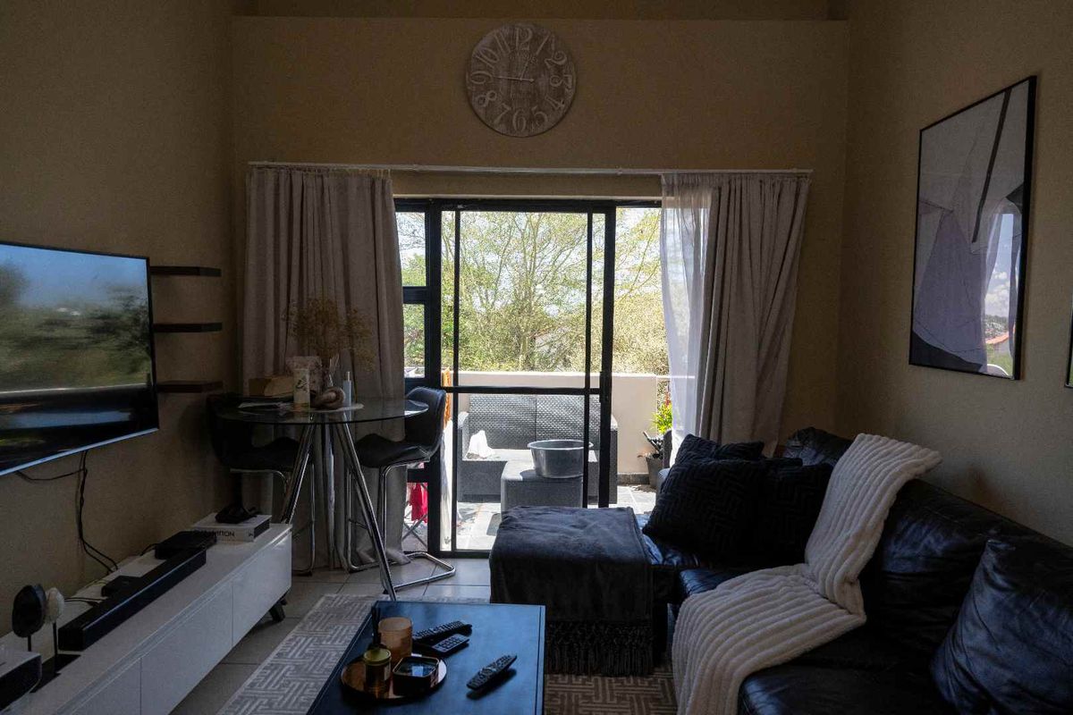 A cozy living room featuring large sliding glass doors that open onto a private balcony, providing natural light and outdoor access.