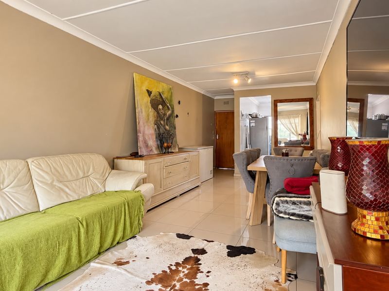 An open-plan living and dining area featuring neutral wall tones, tiled flooring, and a coved ceiling, providing a functional and versatile living space.