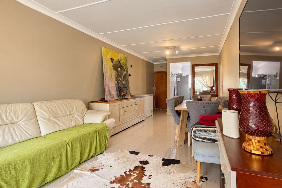 An open-plan living and dining area featuring neutral wall tones, tiled flooring, and a coved ceiling, providing a functional and versatile living space.