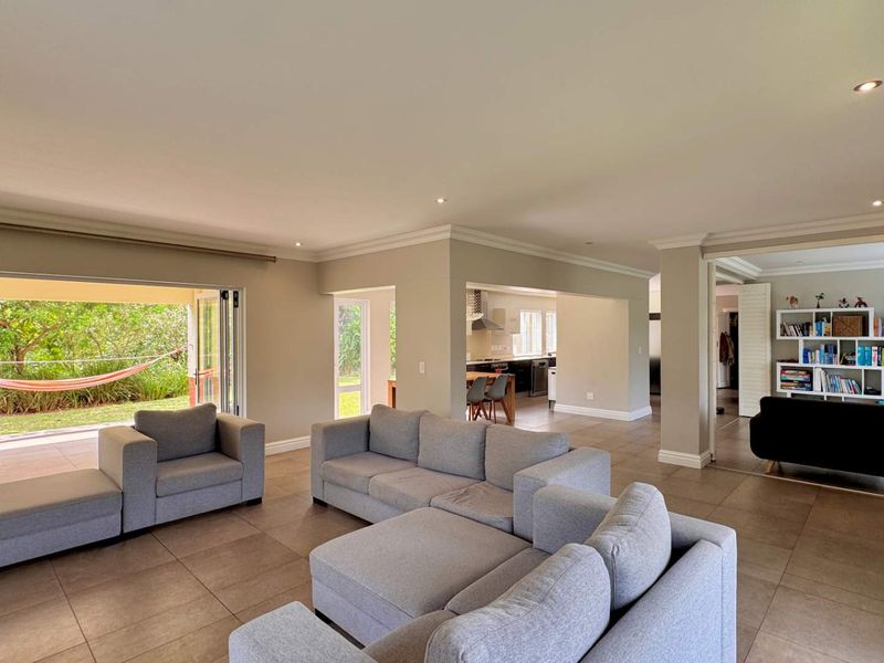Spacious open-plan living area featuring large stacking doors that open to the garden, tiled floors, and recessed lighting, creating a bright and airy atmosphere.
