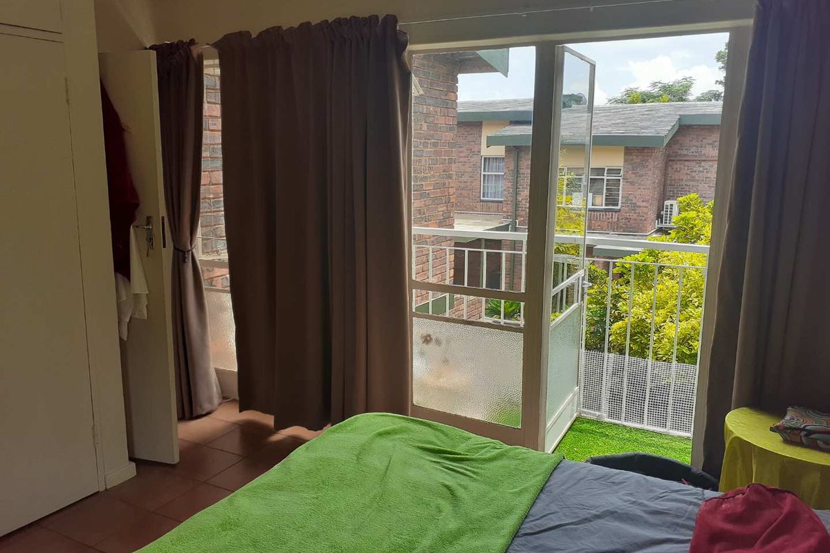 Bedroom featuring tiled flooring, built-in cupboard storage, and direct access to a private balcony with metal railing.