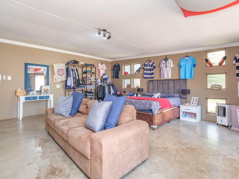 Spacious bedroom featuring polished concrete flooring, track lighting, and multiple small square windows, offering a versatile layout for living and sleeping arrangements.