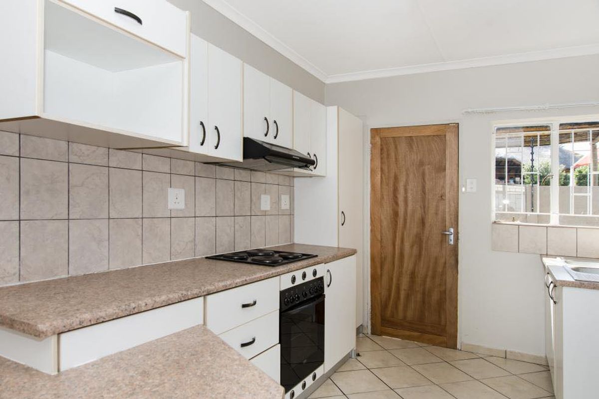 Functional kitchen featuring white cabinetry, built-in oven and hob, extractor fan, tiled backsplash, and tiled flooring with direct access to the exterior.