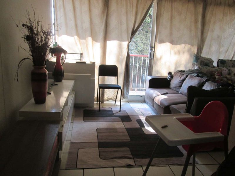 A living room area featuring tiled flooring and a sliding glass door providing access to an outdoor balcony space.