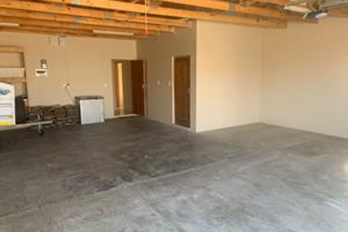 Spacious garage featuring exposed timber ceiling joists and durable concrete flooring, providing ample storage or vehicle parking space with internal access.