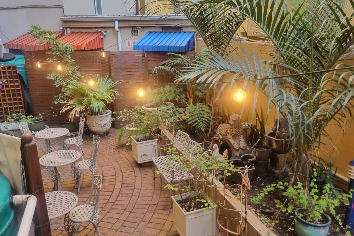 A private rear courtyard featuring brick paving, timber privacy screening, and decorative awnings, creating a cozy outdoor entertainment space.