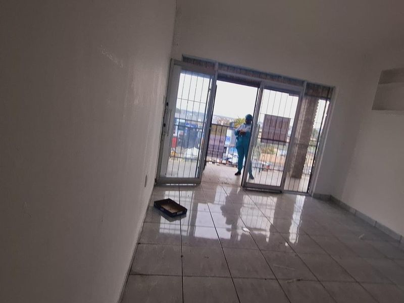 An empty living room featuring tiled flooring and sliding glass doors leading to an outdoor area, providing natural light and access to the exterior.