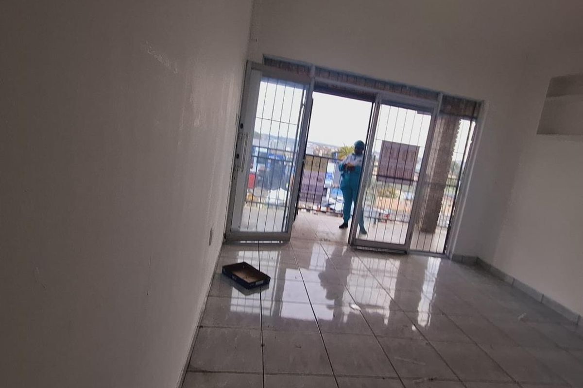 An empty living room featuring tiled flooring and sliding glass doors leading to an outdoor area, providing natural light and access to the exterior.