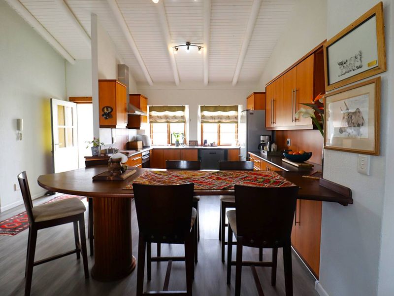 Open-plan kitchen and dining area featuring wooden cabinetry, exposed beam ceilings, and a built-in breakfast bar with modern laminate flooring.