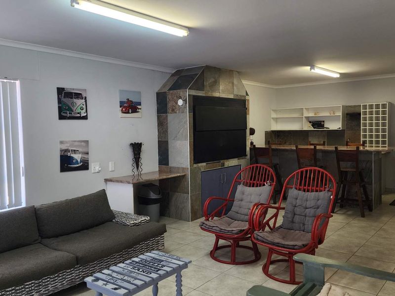 Open-plan living area featuring a built-in indoor braai, tiled flooring, and a breakfast bar, offering a functional space for entertaining.