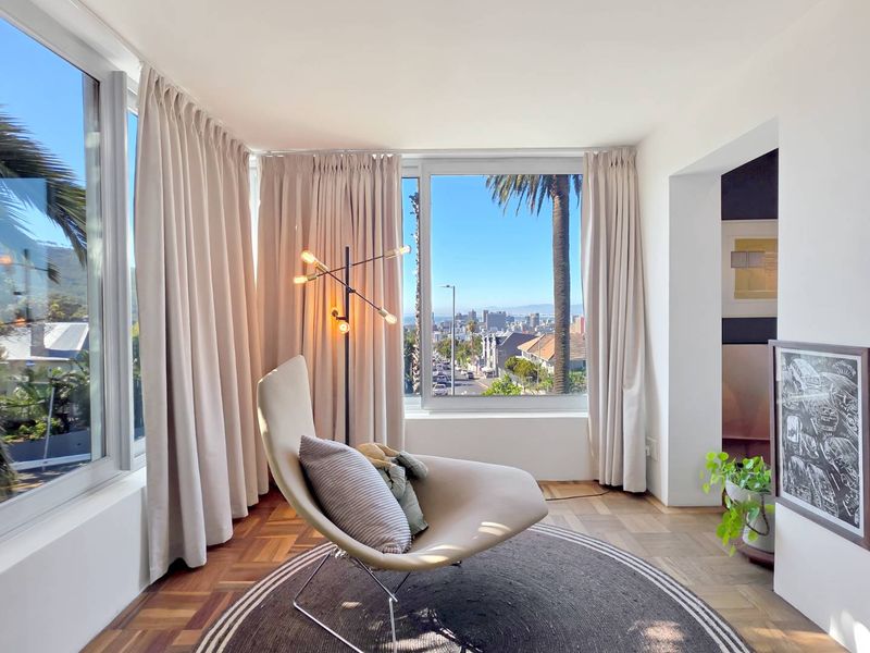 A bright living area featuring beautiful parquet flooring and expansive windows that offer panoramic city and coastal views.