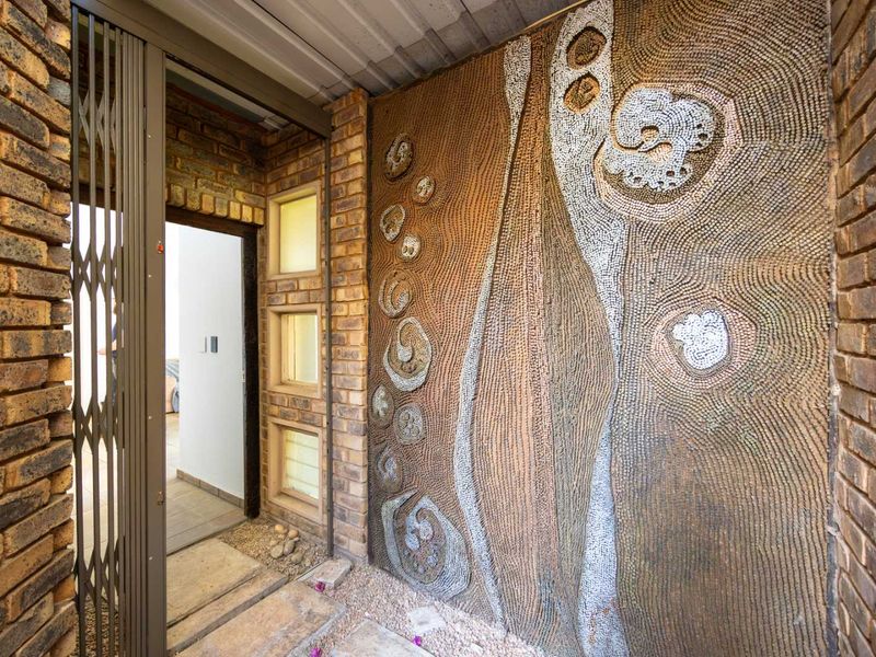 Entrance area featuring exposed brickwork, a security gate, and a unique decorative textured wall feature.