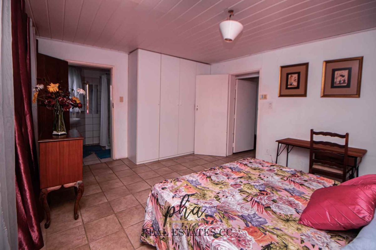 A bedroom featuring built-in cupboards, tiled flooring, and an en-suite bathroom access point.