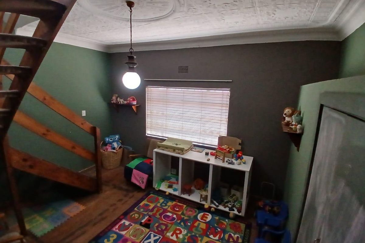 A bedroom featuring a wooden staircase, decorative ceiling rose, and venetian blinds, providing a unique architectural layout.