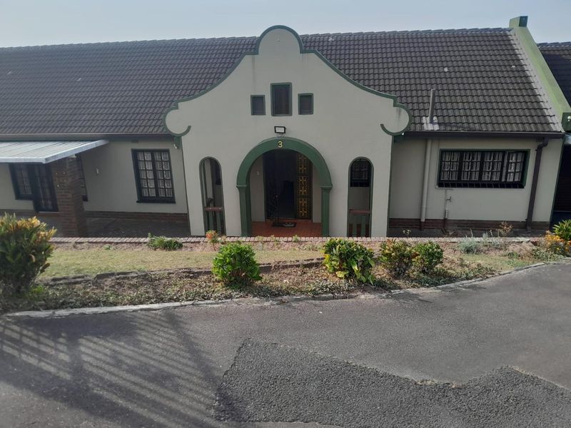 Front elevation of a single-story house featuring a distinctive arched entrance, tiled roof, and a paved driveway.
