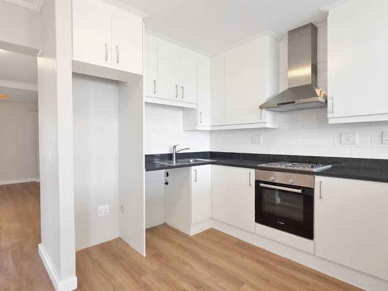 Modern kitchen featuring white cabinetry, granite countertops, subway tile backsplash, and integrated stainless steel appliances including an oven, hob, and extractor fan.