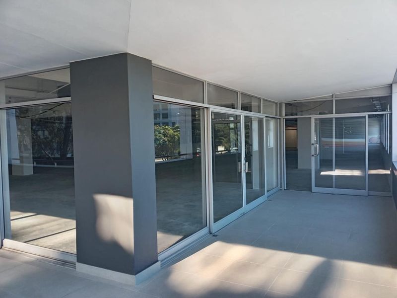 A clean, covered patio area featuring tiled flooring, glass sliding doors, and a modern painted structural column, suitable for commercial use.