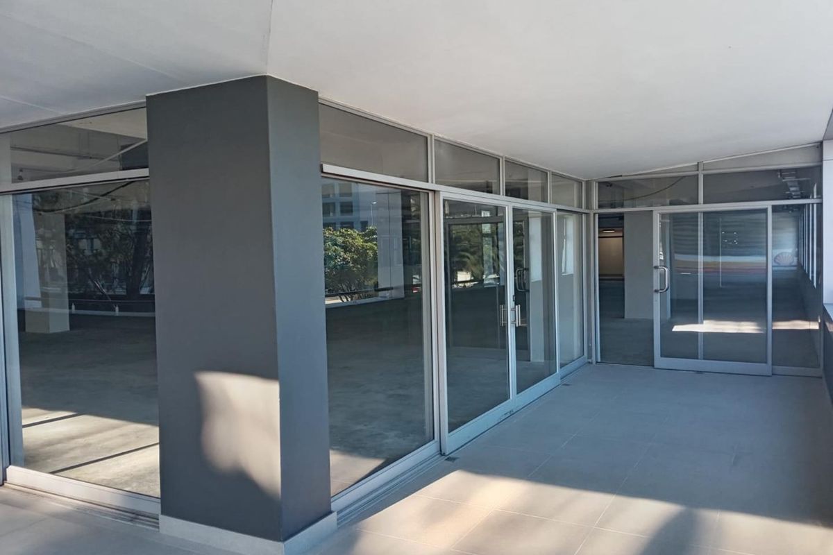 A clean, covered patio area featuring tiled flooring, glass sliding doors, and a modern painted structural column, suitable for commercial use.