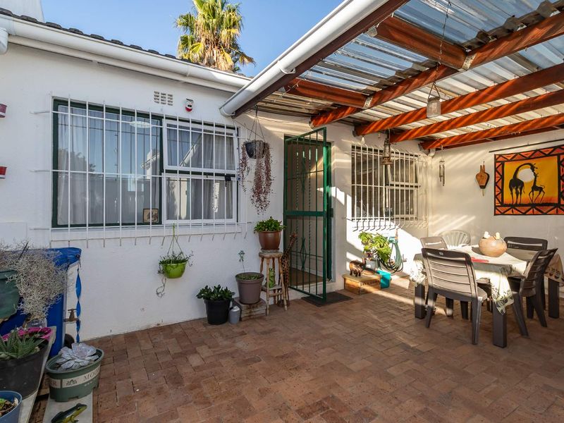 Covered outdoor patio area featuring brick paving, a timber pergola with translucent roofing, and secure window bars.