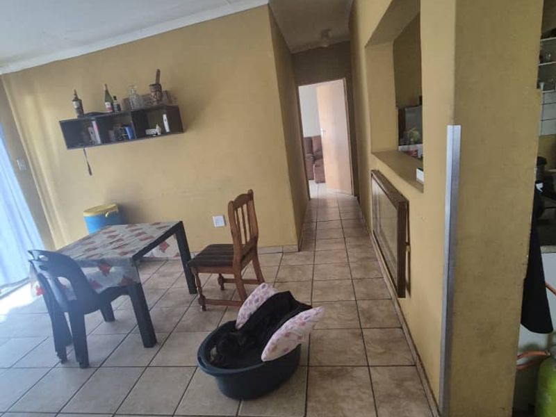 Open plan living area featuring ceramic floor tiles and a convenient pass-through window connecting to the kitchen space.