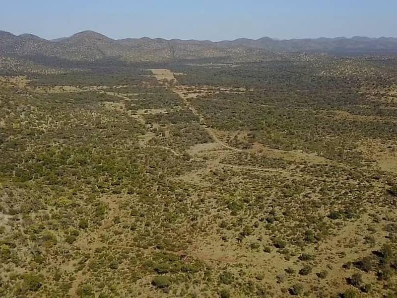 An expansive aerial view of the farm property, showcasing the vast natural landscape, rolling hills, and existing dirt access roads.